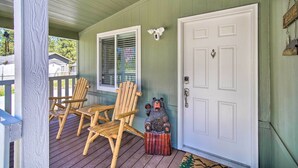 A porch with two wooden chairs, a white door, and a bear statue.