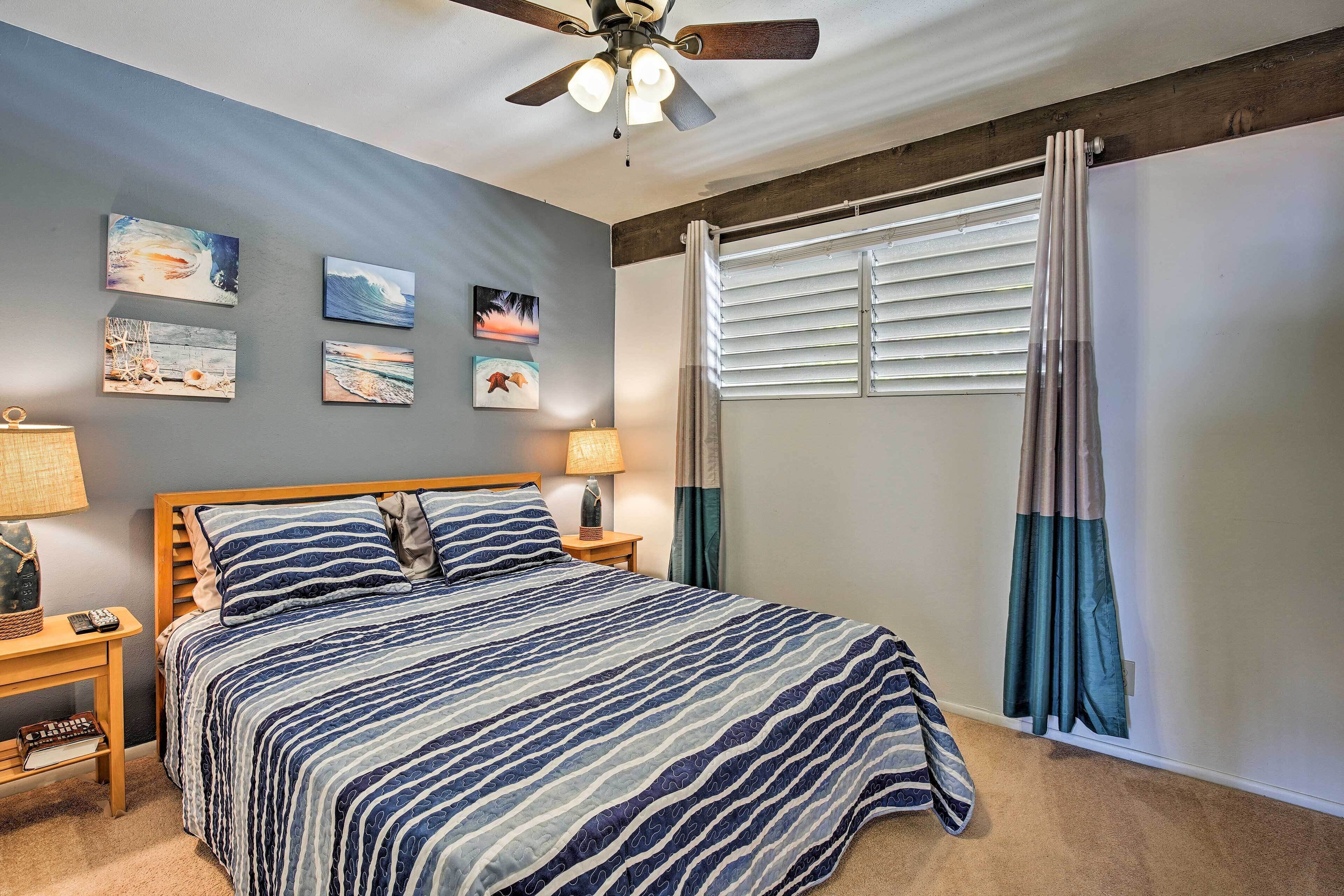 A bedroom with a bed, a ceiling fan, and artwork on the wall.