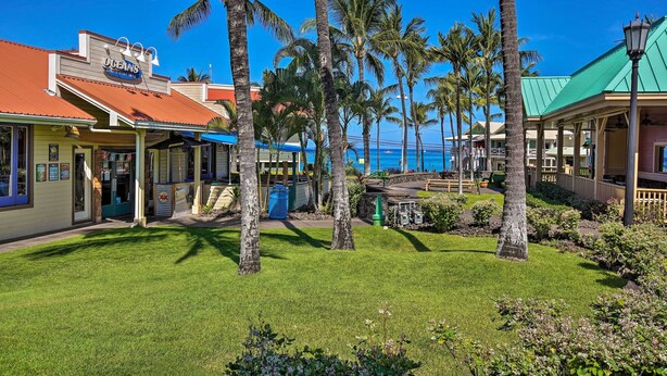 A beachfront hotel with a covered patio, palm trees, and a view of the ocean.