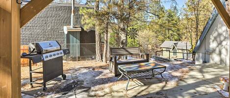 A covered outdoor area with a grill, a bench, and a mushroom decoration.