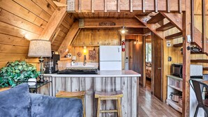 A cozy cabin interior with a wooden interior, a kitchen with a central island, and a dining area. - Cozy A-frame w/ Hot Tub Near Arrowbear Lake! (Running Springs)