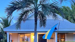 A house with a blue roof, a palm tree, and red flowers in the front yard. - 🇧🇸 GEAUX FISH Spanish Wells Sea Swings kayak beach snorkel gear! FREE GIFT 🏝️🩵💛🖤🇧🇸 (Spanish Wells)