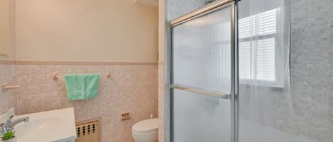 A bathroom with a shower, toilet, sink, and a towel hanging on the wall.