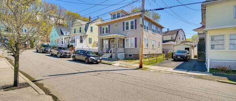Une rue résidentielle bordée de maisons, de voitures garées et de poteaux électriques.