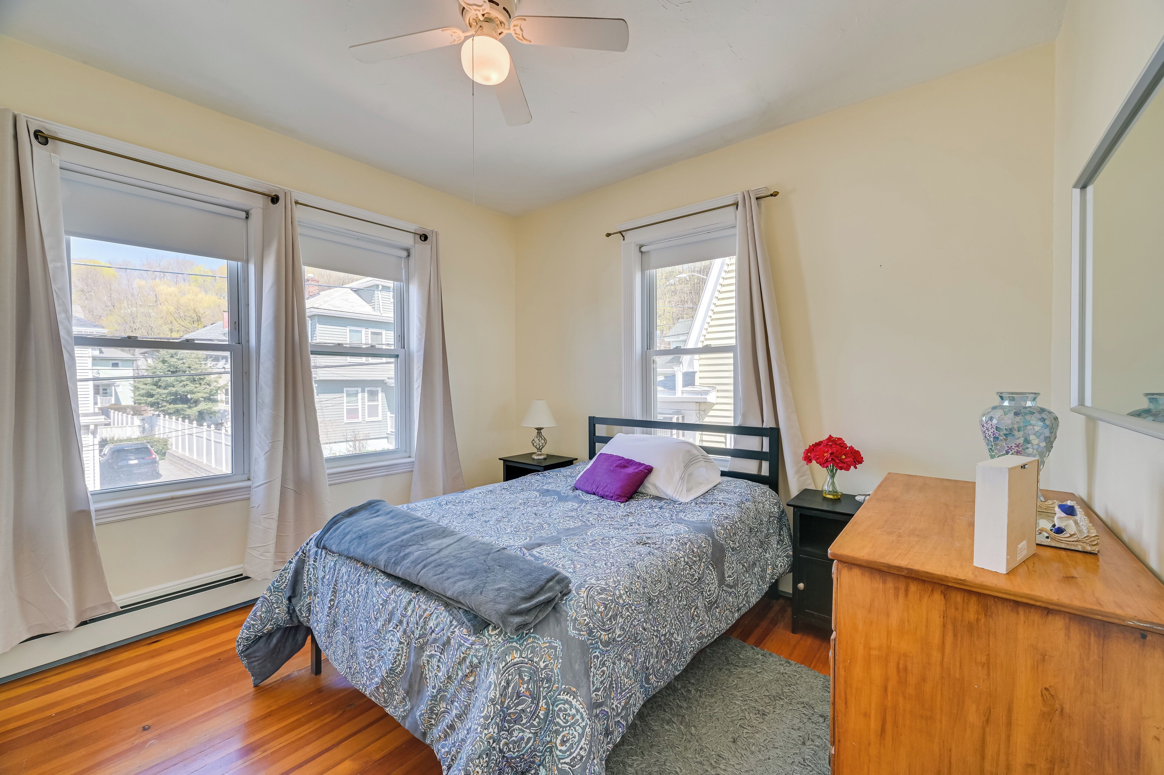 A bedroom with a bed, nightstand, dresser, and a ceiling fan.