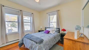 A bedroom with a bed, nightstand, dresser, and a ceiling fan.