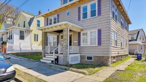 A two-story residential building with a porch, a garage, and a small front yard. - Boston Area Vacation Rental 3 Mi to Airport! (Revere)