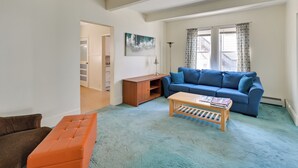 A living room with a blue sofa, a wooden coffee table, and a brown armchair. - Boston Area Vacation Rental 3 Mi to Airport! (Revere)