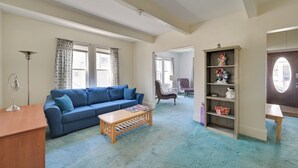 A living room with a blue sofa, wooden coffee table, and a bookshelf with decorative items. - Boston Area Vacation Rental 3 Mi to Airport! (Revere)