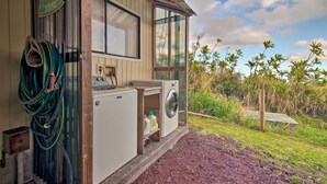 A laundry facility with a washing machine and dryer, a hose, and a sign indicating laundry services. - Hilo Couples Retreat ~ 6 Miles to Honoli'i Beach! (Hilo)
