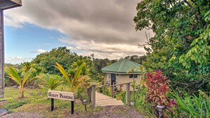 A guest parking area with a sign, a wooden staircase leading to a building with a green roof, surrounded by lush greenery. - Hilo Couples Retreat ~ 6 Miles to Honoli'i Beach! (Hilo)