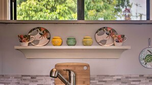 A kitchen with a wooden cutting board, a stainless steel sink, and a window with a view of greenery. - Hilo Couples Retreat ~ 6 Miles to Honoli'i Beach! (Hilo)