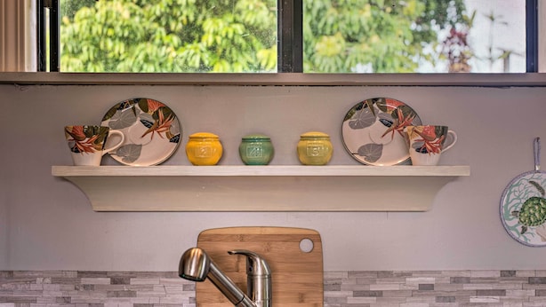 A kitchen with a wooden cutting board, a stainless steel sink, and a window with a view of greenery. - Hilo Couples Retreat ~ 6 Miles to Honoli'i Beach! (Hilo)
