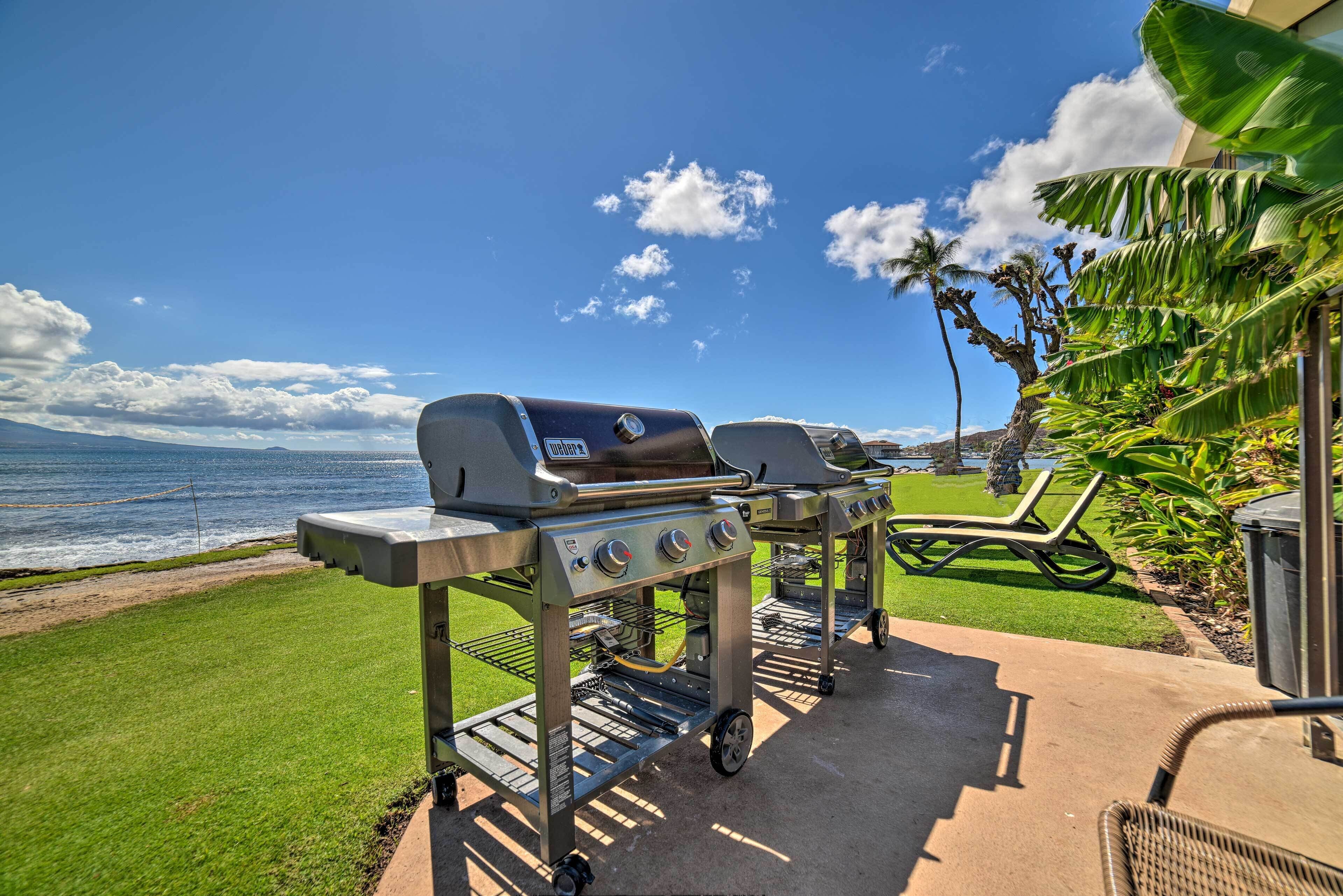 A patio with two portable grills, a lounge chair, and a view of the ocean.