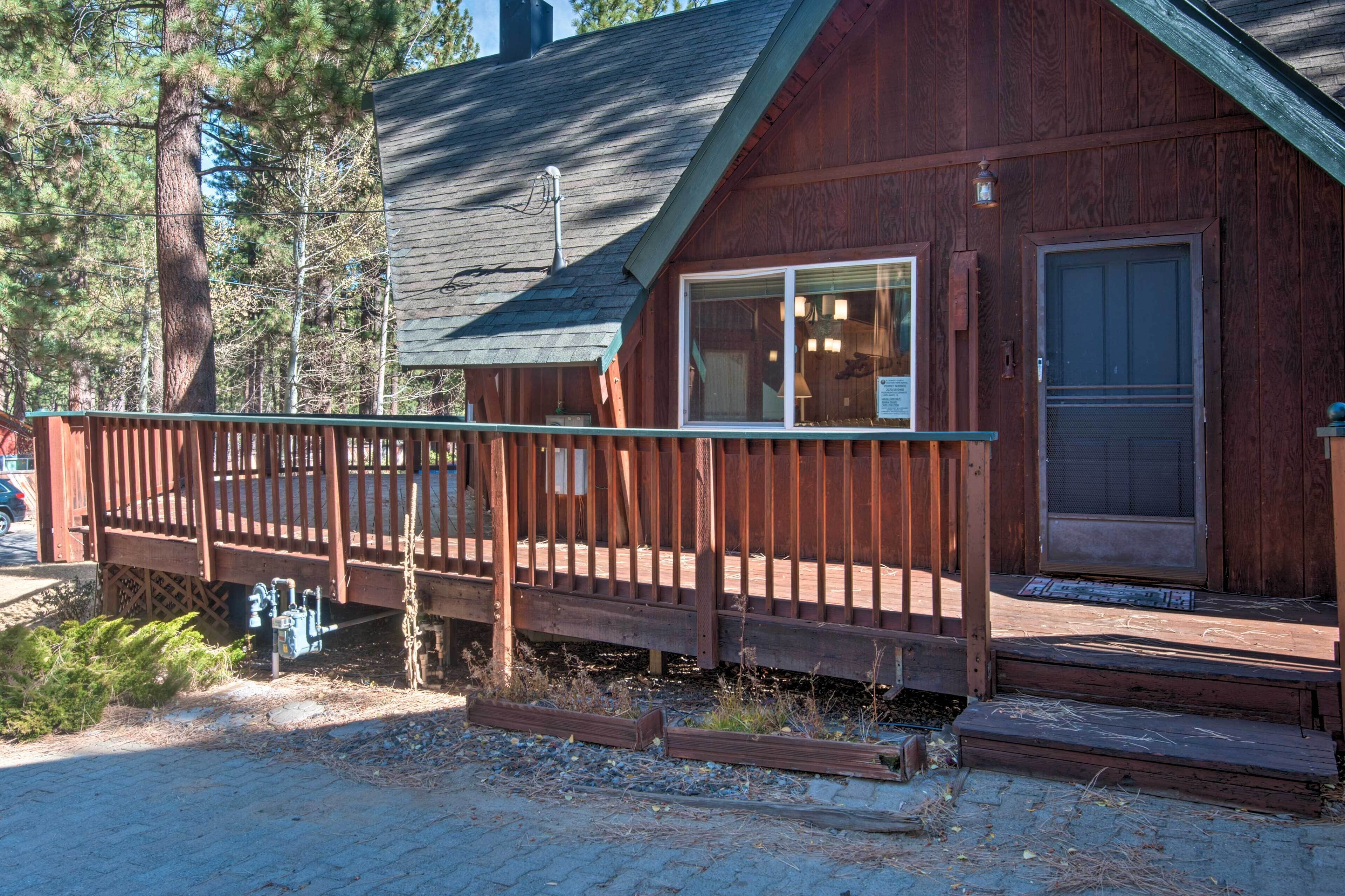 A wooden cabin with a porch, a door, and a window.
