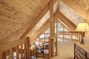 Un intérieur en bois avec un plafond haut, un escalier et une vue sur l’extérieur.