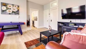 Una sala de estar con mesa de billar, televisor y sofá.