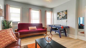 A living room with a red sofa, a pool table, and a heart-shaped decoration on a table.