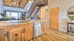 A spacious kitchen with wooden cabinets, a stainless steel dishwasher, a marble countertop, and a wooden staircase leading to an upper level. - Airy Oceanfront Kailua-kona Gem w/ Community Pool (Kailua-Kona)