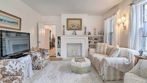 A living room with a fireplace, a television, and a bookshelf. - Charming Nineteenth-century Cape Code Escape (Centerville)