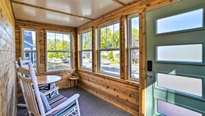 A cozy room with wooden walls, a green door, and large windows offering a view of the street. - Pet-friendly Minneapolis Home ~ 6 Mi to Dtwn! (Minneapolis)