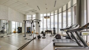Une salle de sport équipée de tapis de course, d’appareils de musculation et d’un mur recouvert de miroirs.