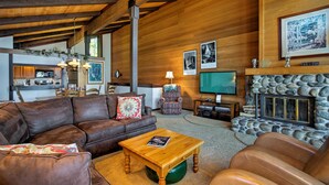 A cozy living room with a stone fireplace, leather furniture, and a television. - 11 Mi to Palisades Tahoe: Lakefront Home w/ View! (Tahoe City)