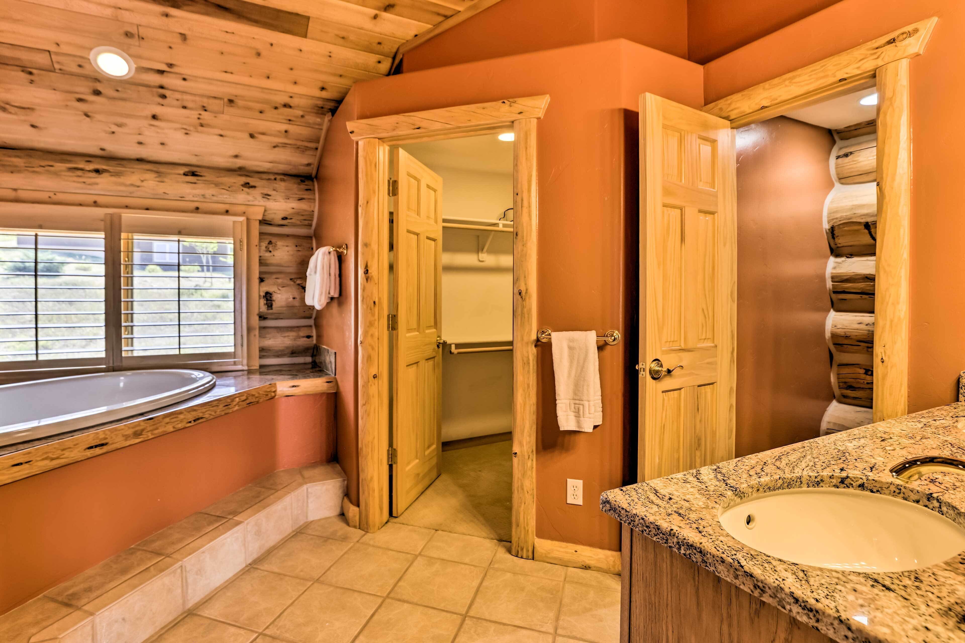 A bathroom with a wooden ceiling, a bathtub, a sink, and a shower area.