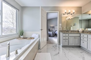 A modern bathroom with a large bathtub, a walk-in shower, and a vanity with a mirror.
