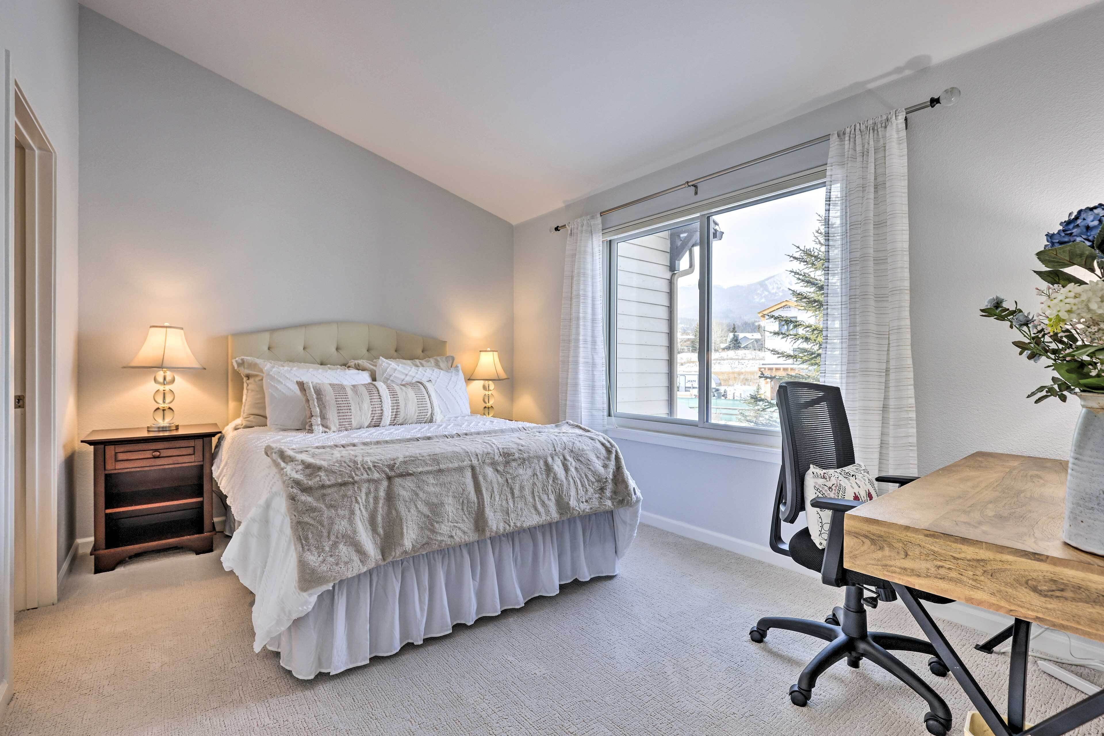A bedroom with a bed, bedside tables, a desk, and a window.