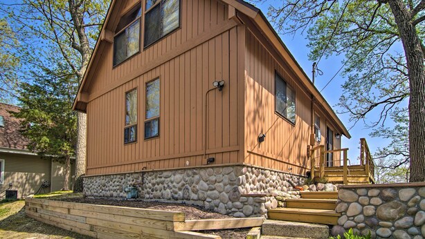 Une maison en bois à deux étages, avec des fondations en pierre et une terrasse en bois.
