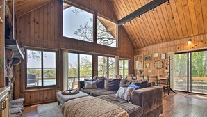 Un salon spacieux avec un grand plafond en bois, un confortable canapé marron et une cheminée en pierre.