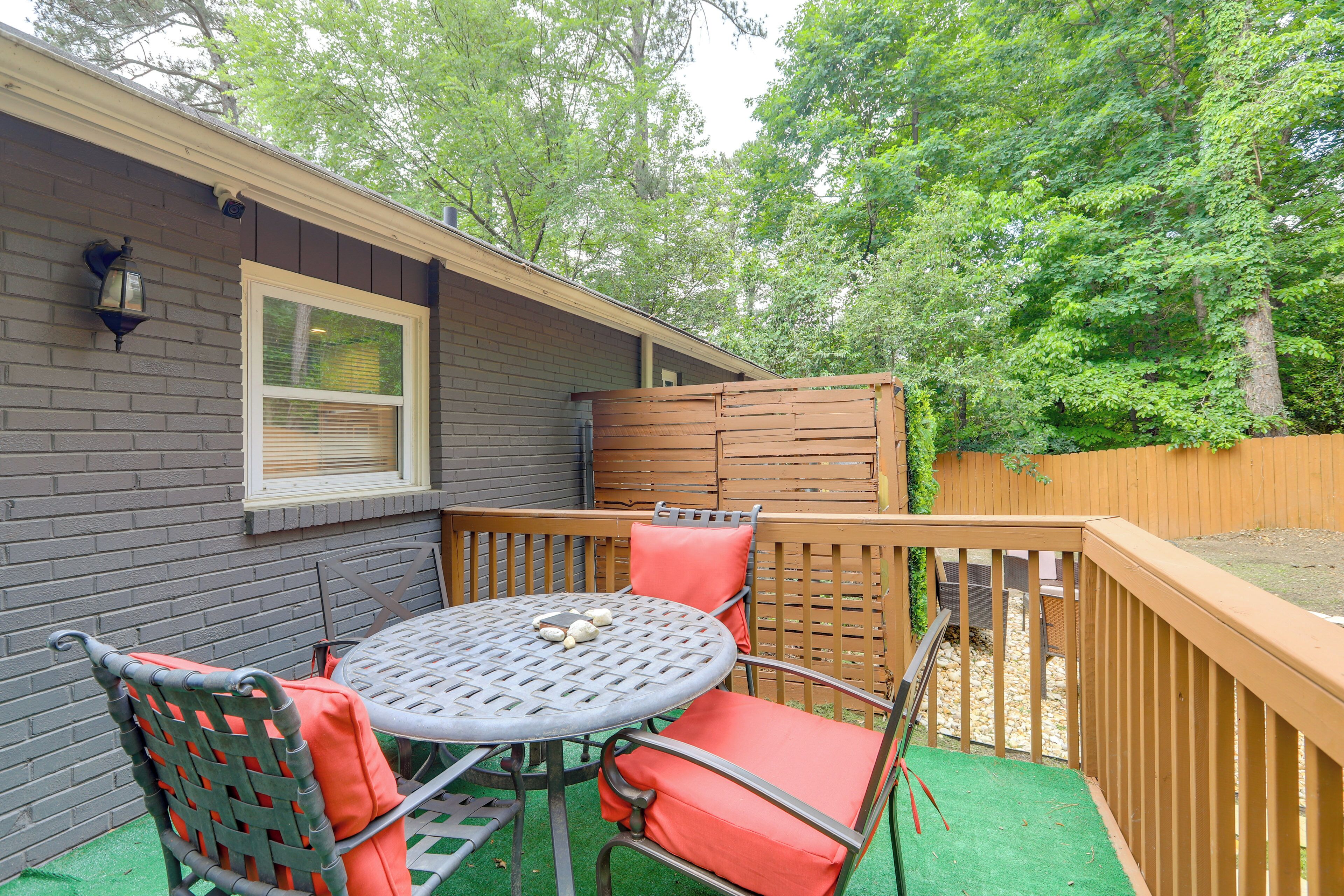 A patio with a table and chairs, a wooden fence, and a brick wall.