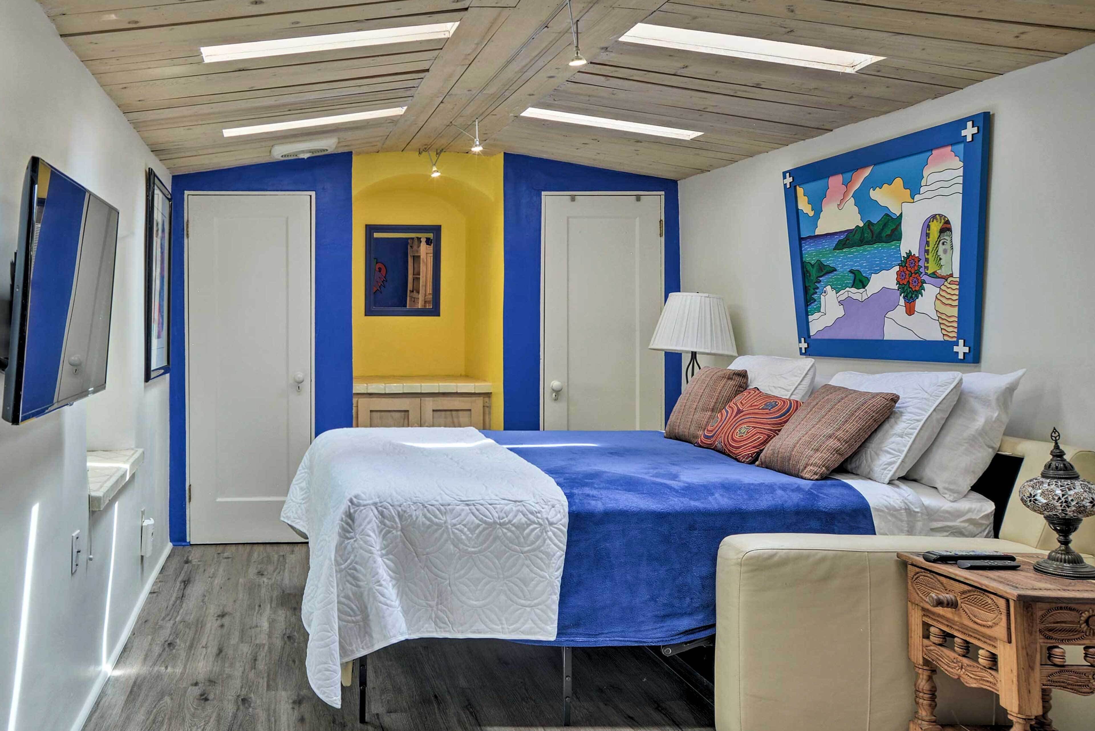 A bedroom with a bed, a bedside table, a lamp, and a painting on the wall.