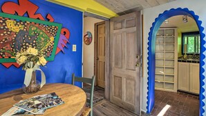 A dining area with a wooden table, chairs, a vase with flowers, and a colorful wall art piece. - Charming Casita Studio - Near Santa Fe Plaza! (Santa Fe)