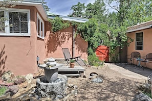 A patio area with a stone fountain, lounge chairs, and a small table with a potted plant.
