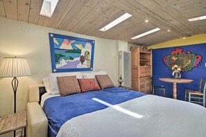 Relax in a spacious room with a large bed, wooden headboard, and a beautiful landscape painting above.