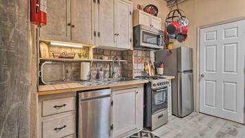 Una cocina con armarios de madera, microondas, estufa, refrigerador y lavavajillas.