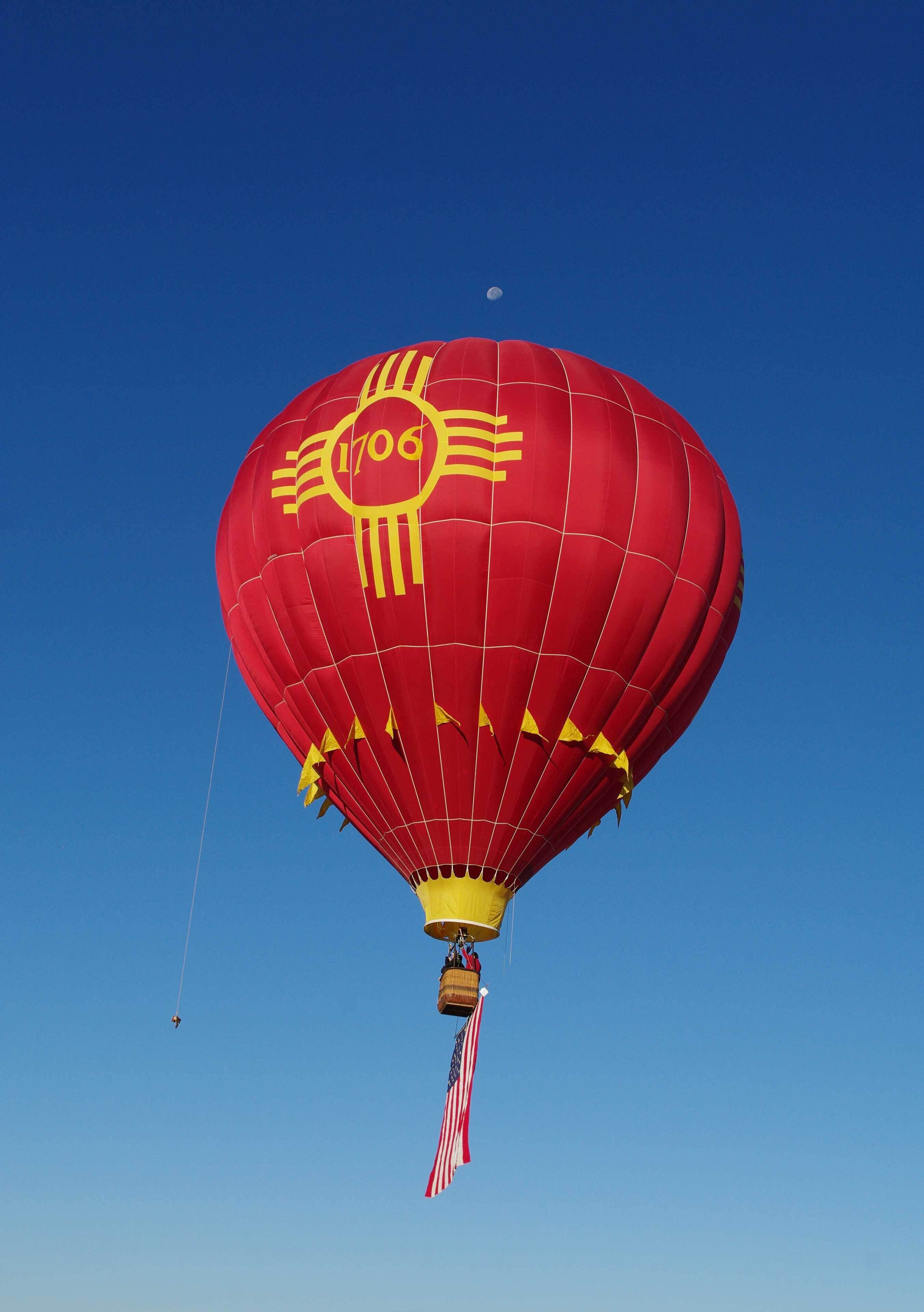 Una mongolfiera rossa con un disegno del sole e il numero 1706.