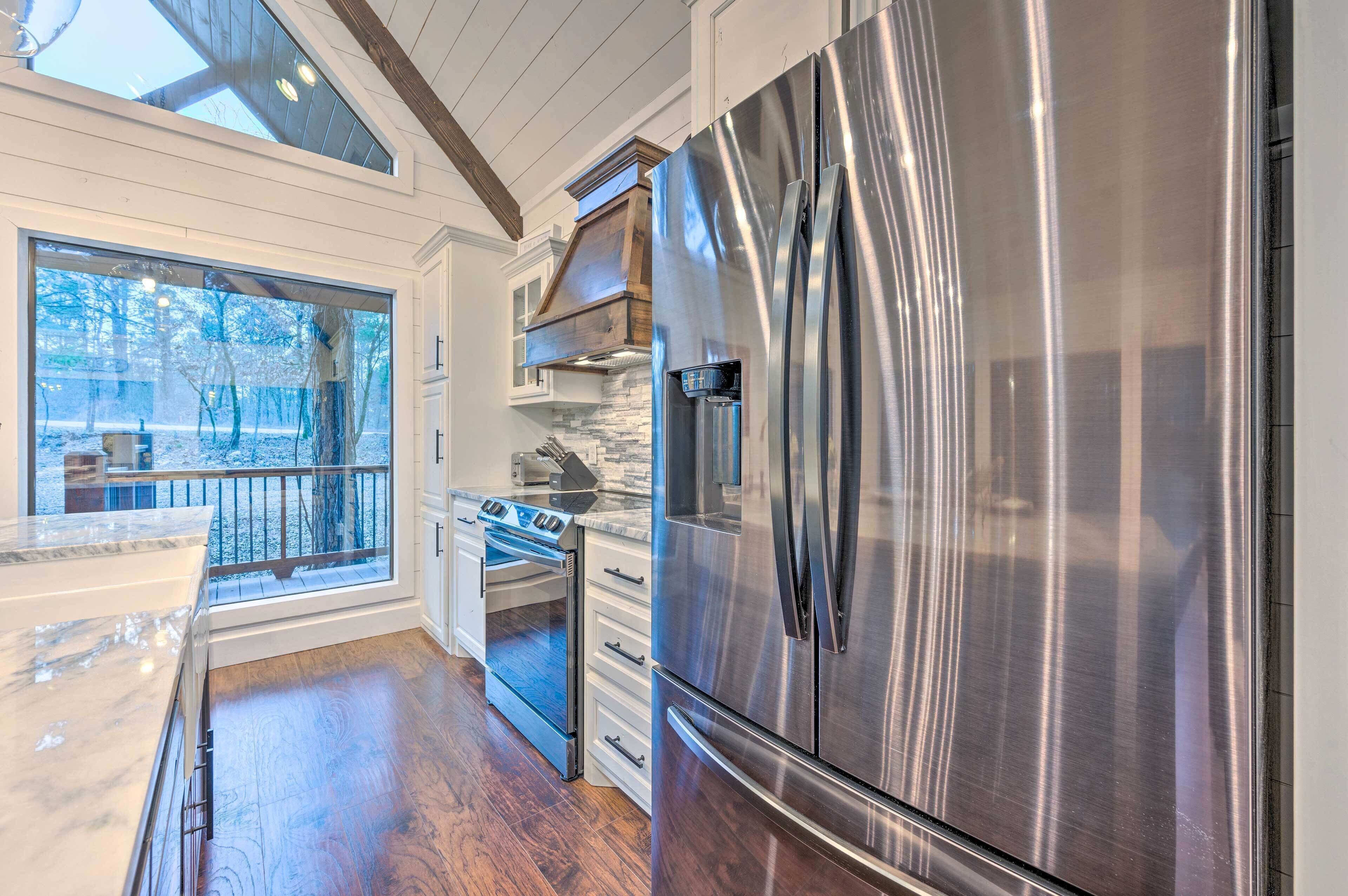 A modern kitchen with a large stainless steel refrigerator, a built-in oven, and a stone backsplash.