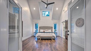 A bedroom with a large bed, a ceiling fan, and a skylight. - Modern Cabin w/ Hot Tub: 1 Mi From Hochatown! (Broken Bow)