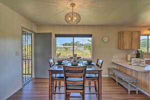 Un comedor con una mesa dispuesta para cuatro personas, un banco de madera y vistas al exterior a través de un ventanal.