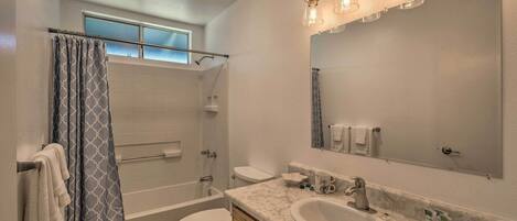 A bathroom with a bathtub, toilet, sink, and a large mirror.