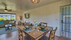Uma sala de jantar com uma mesa de madeira posta para quatro pessoas, cercada por cadeiras.