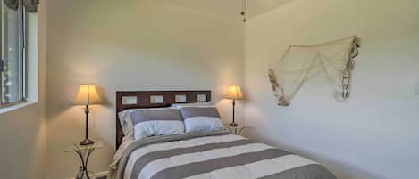 Un dormitorio con una cama, dos lámparas de noche, un ventilador de techo y un adorno en la pared.