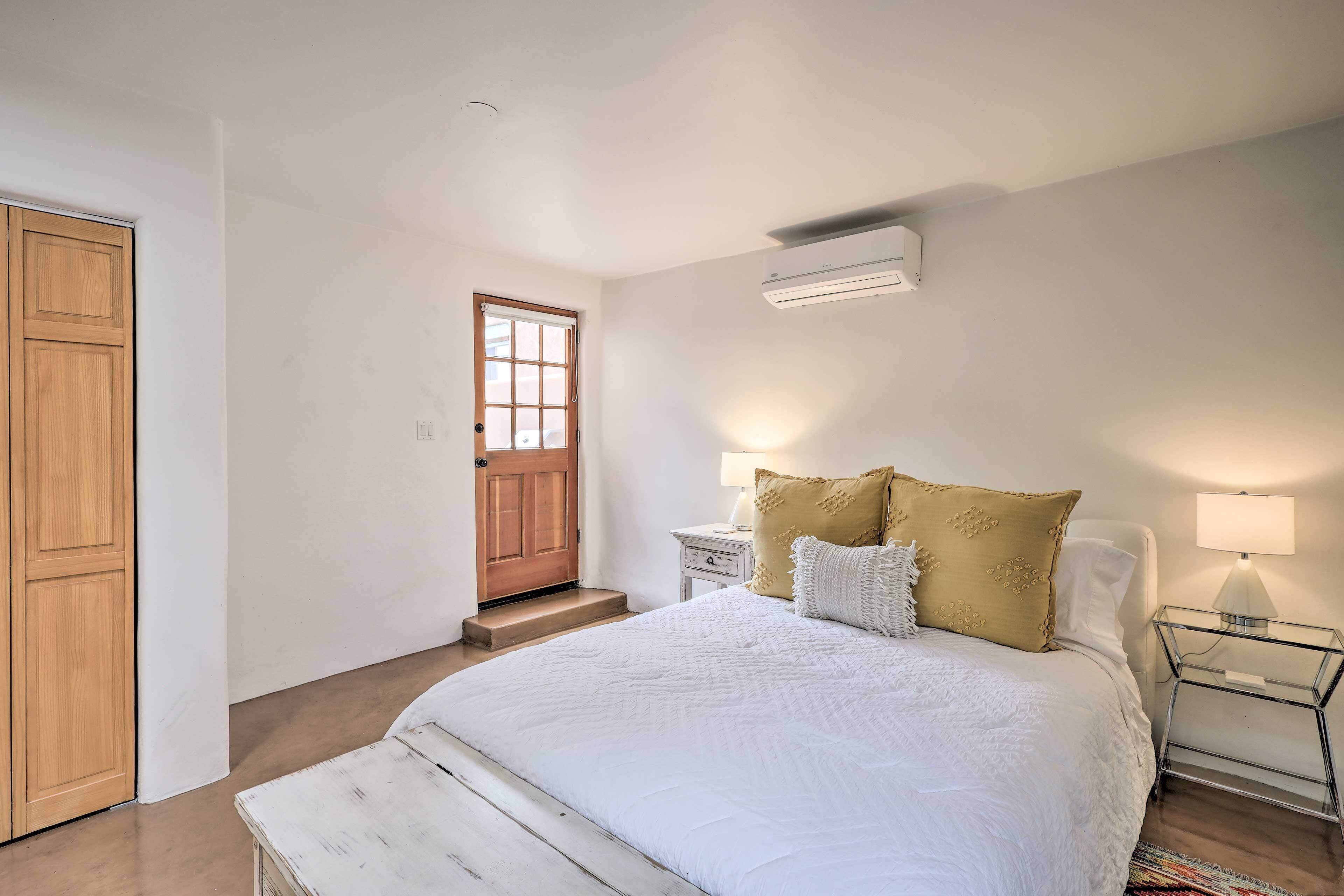 A bedroom with a bed, bedside tables, a wardrobe, and an air conditioning unit.