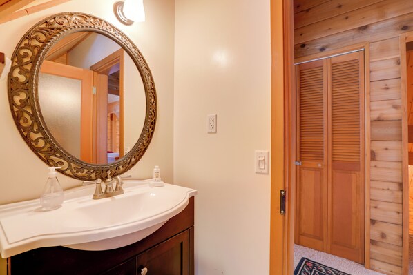 Une salle de bain avec un grand miroir décoratif, un lavabo blanc et des portes en bois.