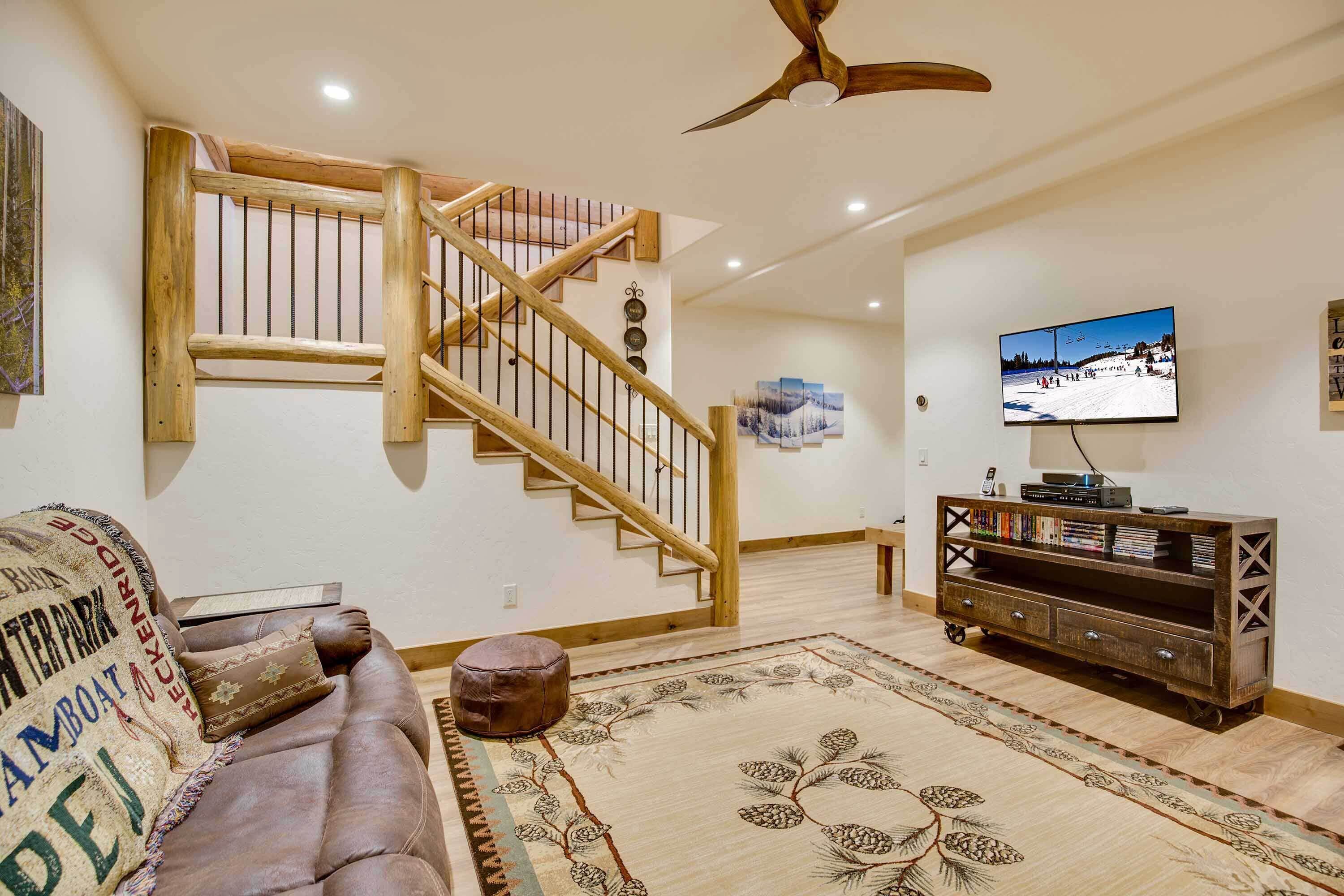 A living room with a wooden staircase, a television, a sofa, and a patterned rug.