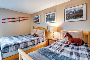 Ein Schlafzimmer mit zwei Betten, einem angebrachten Skiregal und gerahmten Bildern an der Wand.