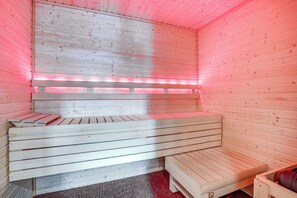 Eine Sauna mit Holzbänken und einer rot beleuchteten Decke.